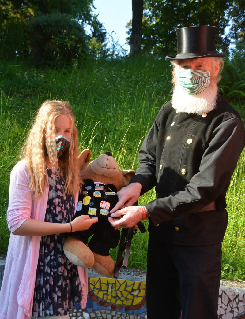 Werner Überdick und seine Enkelin Nele mit Glückstour-Maskottchen „Hermann“. Die Anstecker zeigen Collagen, gemalt für die Glückstour von krebskranken Kindern.